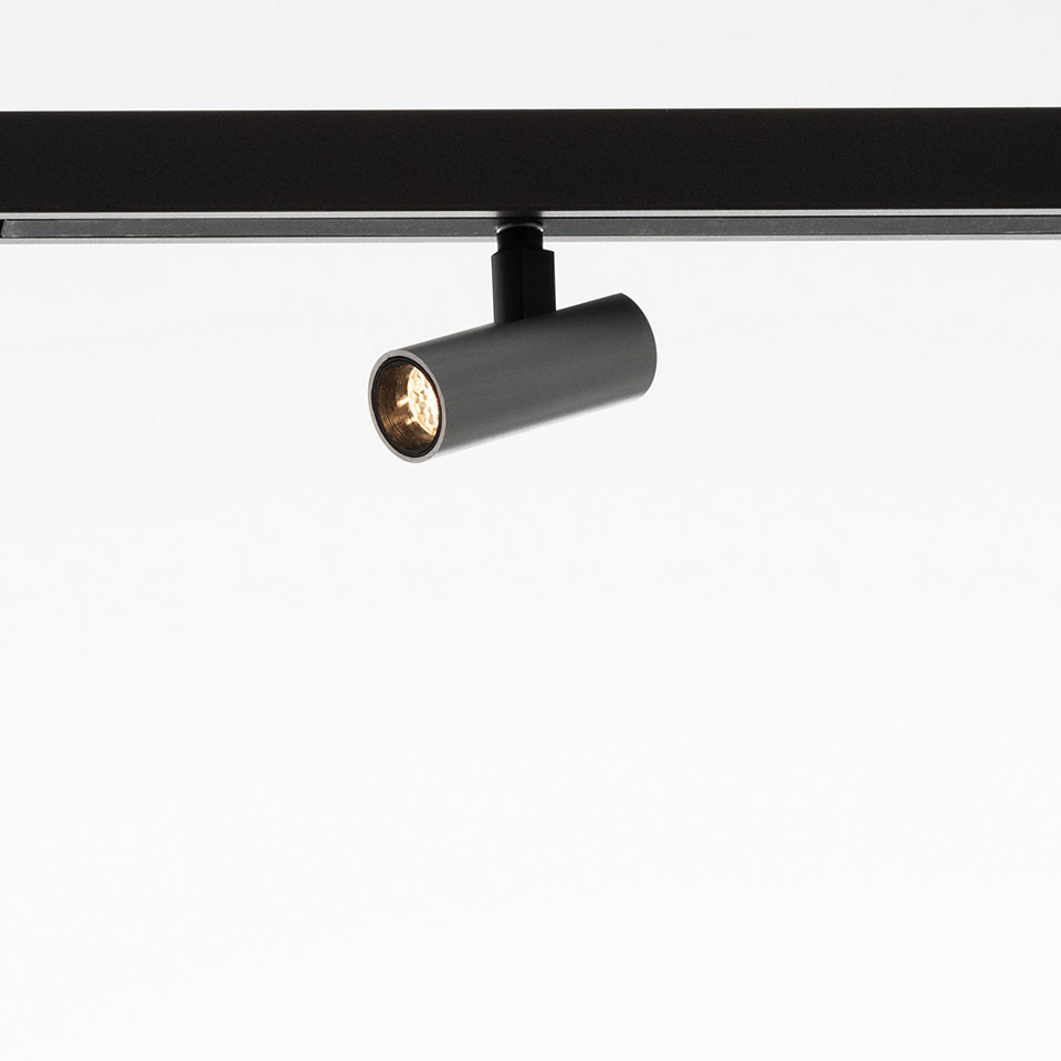 Artemide Turn Around System: faretto cilindrico grigio orientabile montato su binario nero, diretto verso il basso