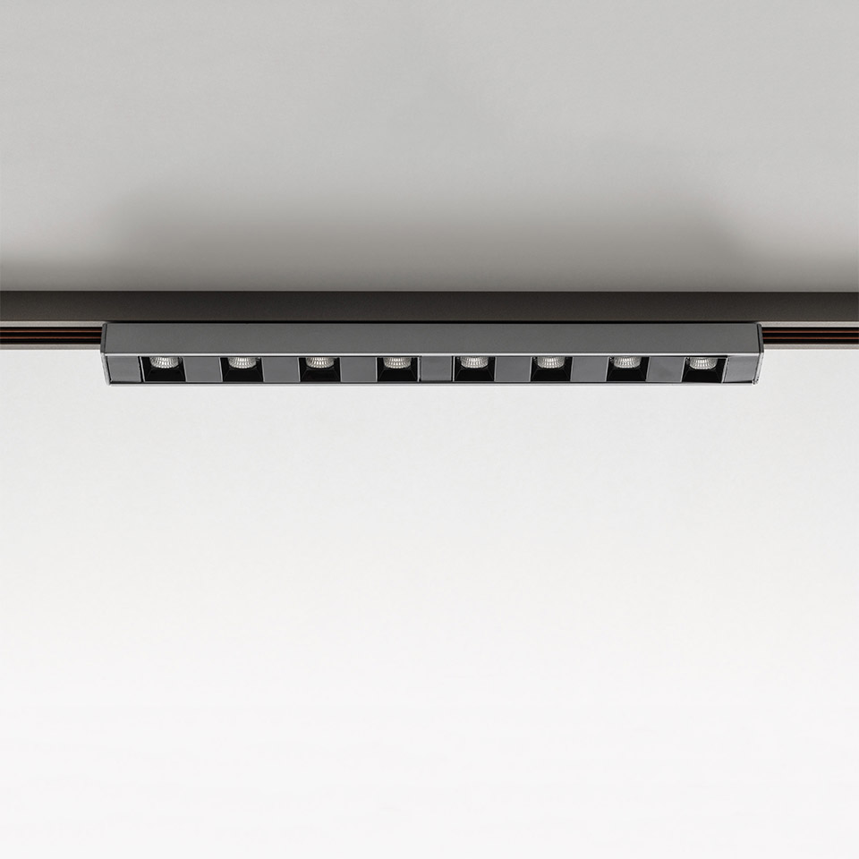 Artemide Turn Around System: barra LED lineare nera con 9 faretti quadrati orientabili montata su binario a soffitto