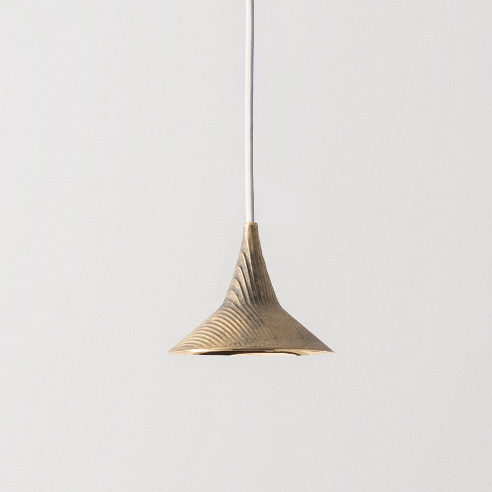 Lampada a sospensione Artemide Unterlinden con paralume svasato in ottone con texture a costole concentriche, sospesa da un sottile cavo bianco