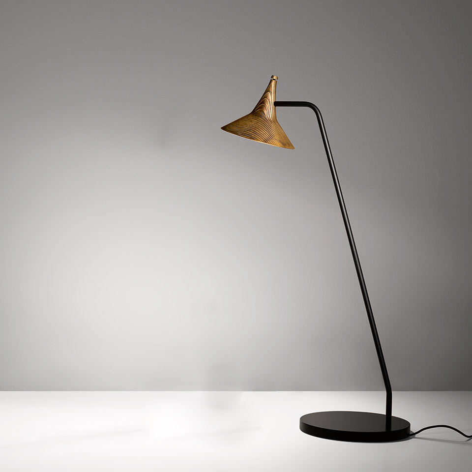 Lampada da terra Artemide Unterlinden: stelo nero sottile su base rotonda, braccio angolato, paralume conico dorato con motivo a costine