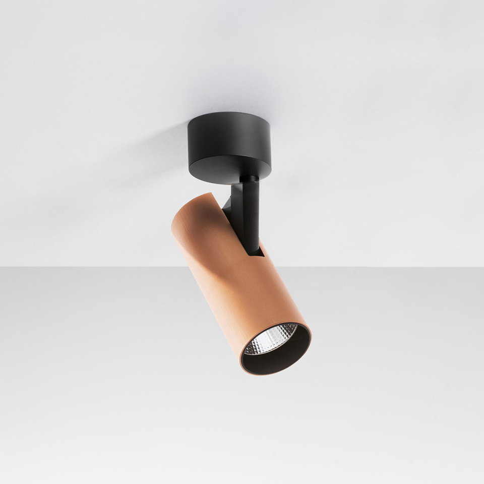 Artemide Vector Ceiling spotlight: adjustable copper-tone cylindrical LED head on black ceiling mount, directed downward at an angle