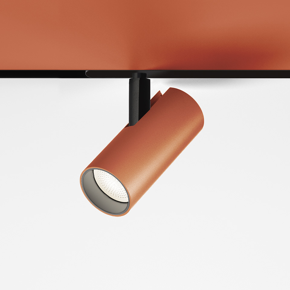 Faretti da binario Artemide Vector Magnetic in finitura terracotta, corpo cilindrico su supporto nero, orientato verso il basso con sorgente LED