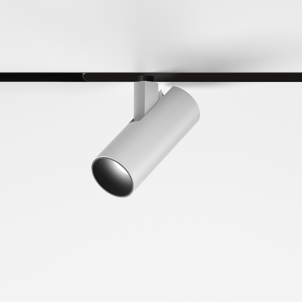 Faretto da binario Artemide Vector Magnetic bianco, corpo cilindrico inclinato su binario magnetico nero, apparecchio LED direzionale