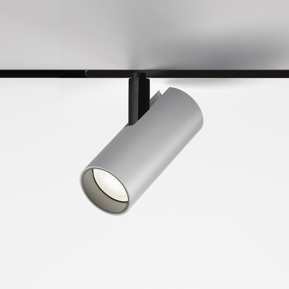 Faretto da binario magnetico Artemide Vector Magnetic: testa cilindrica grigia a LED montata su binario magnetico nero, inclinata verso il basso
