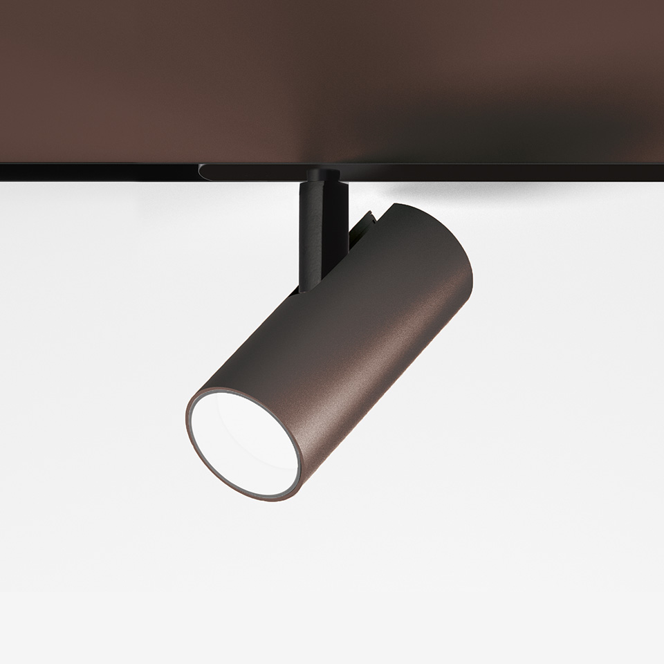 Faretto da binario Artemide Vector Magnetic in finitura bronzo, corpo cilindrico su supporto nero, inclinato verso il basso con ottica LED bianca