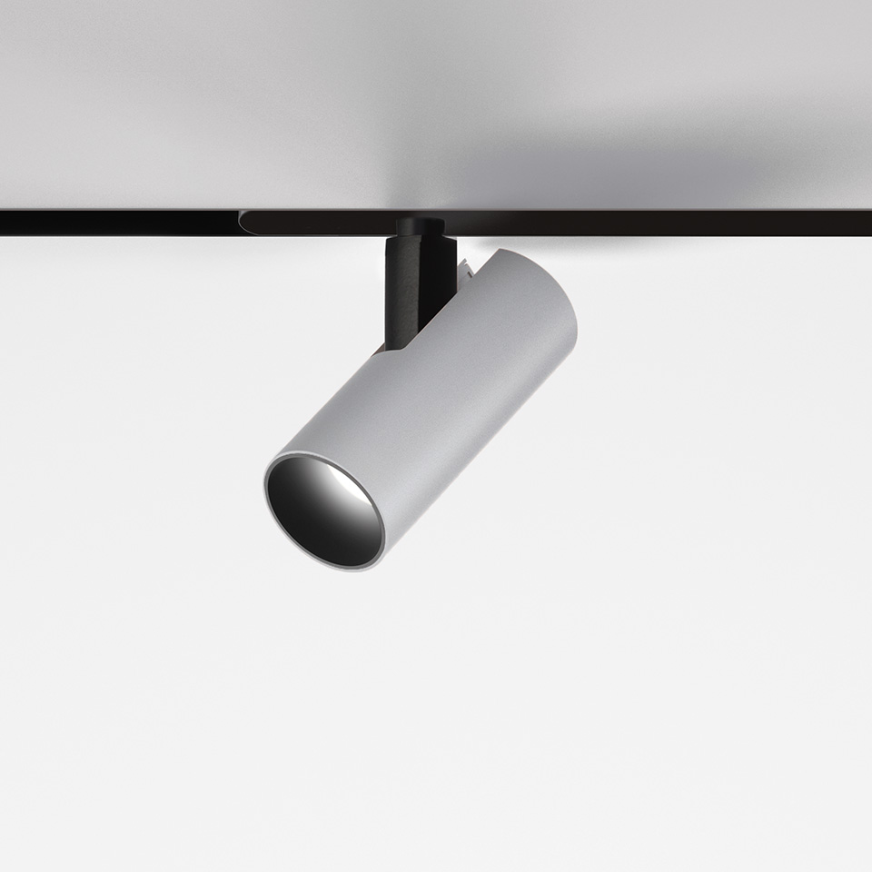 Faretto da binario Artemide Vector Magnetic, corpo cilindrico bianco inclinato verso il basso, montato su sistema a binario magnetico nero