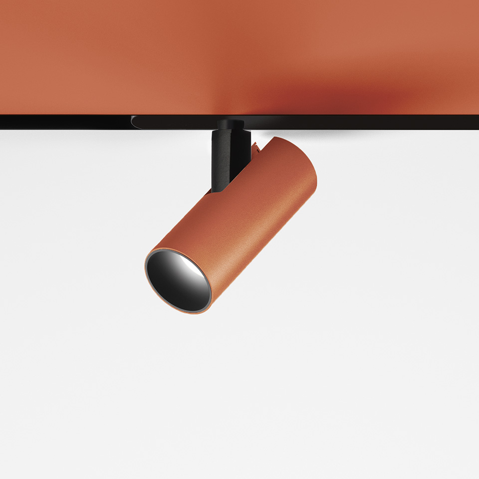 Faretto su binario magnetico Artemide Vector Magnetic in finitura terracotta, corpo cilindrico su supporto nero, testa direzionale orientabile