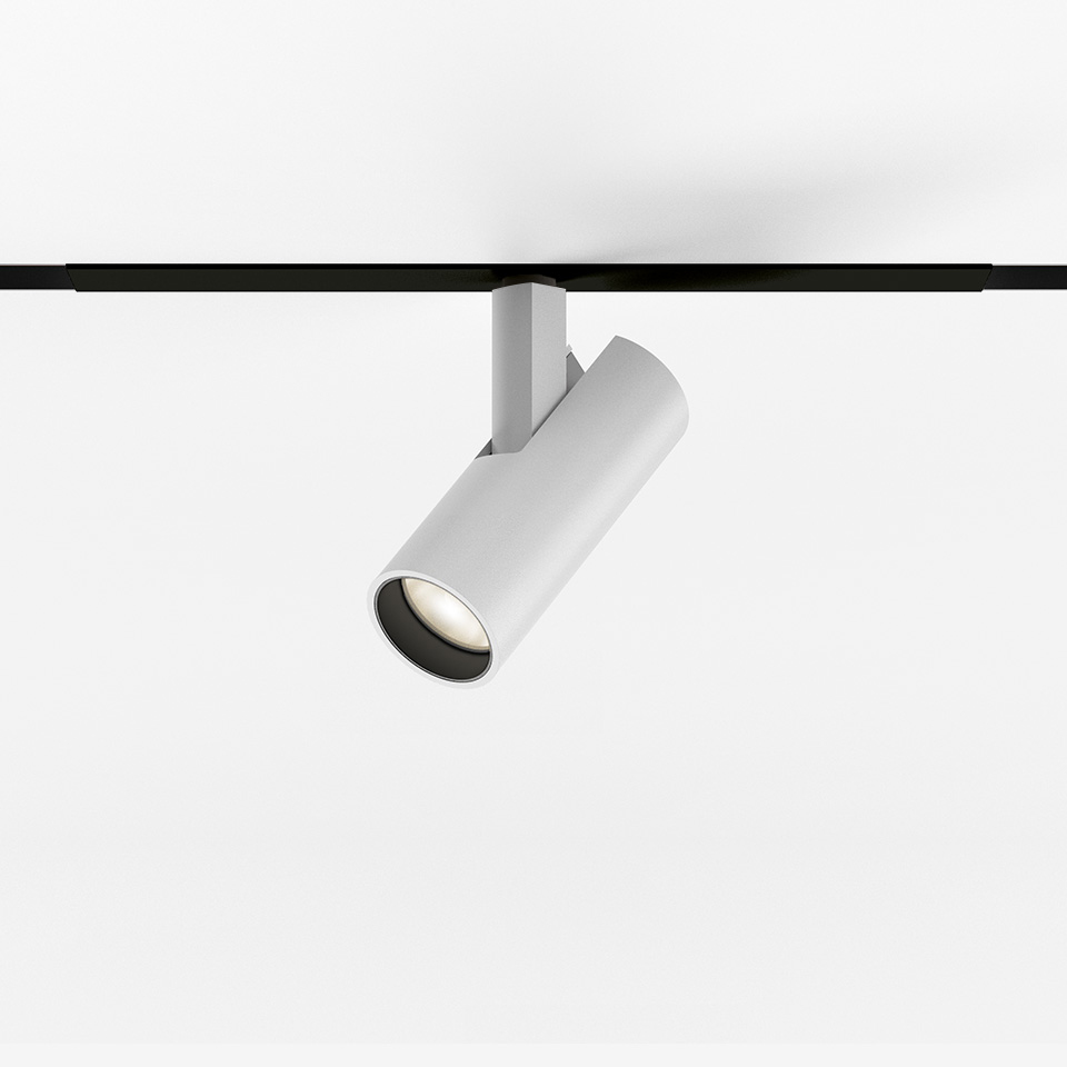 Faretto da binario magnetico Artemide Vector Magnetic bianco, corpo cilindrico inclinato su binario magnetico nero, con sorgente LED
