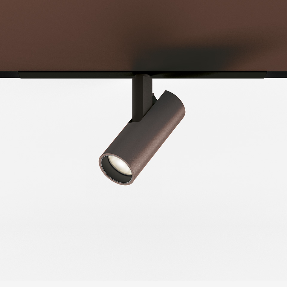 Faretto da binario Artemide Vector Magnetic in finitura bronzo, corpo cilindrico, montato su binario magnetico nero, LED direzionale regolabile
