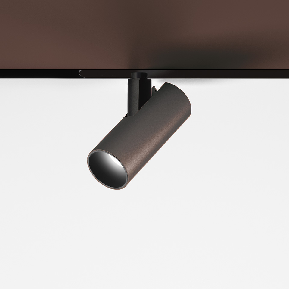 Faretto da binario Artemide Vector Magnetic in finitura bronzo, corpo cilindrico, testa orientabile su binario magnetico nero