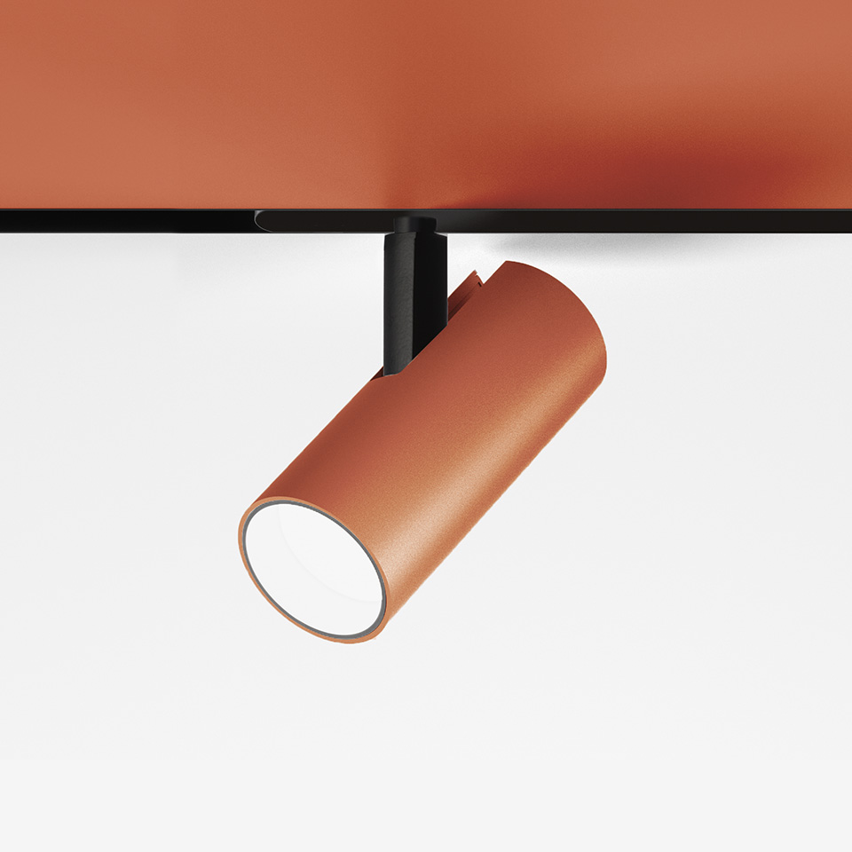 Faretto da binario Artemide Vector Magnetic in finitura terracotta, corpo cilindrico su supporto a binario nero, inclinato verso il basso