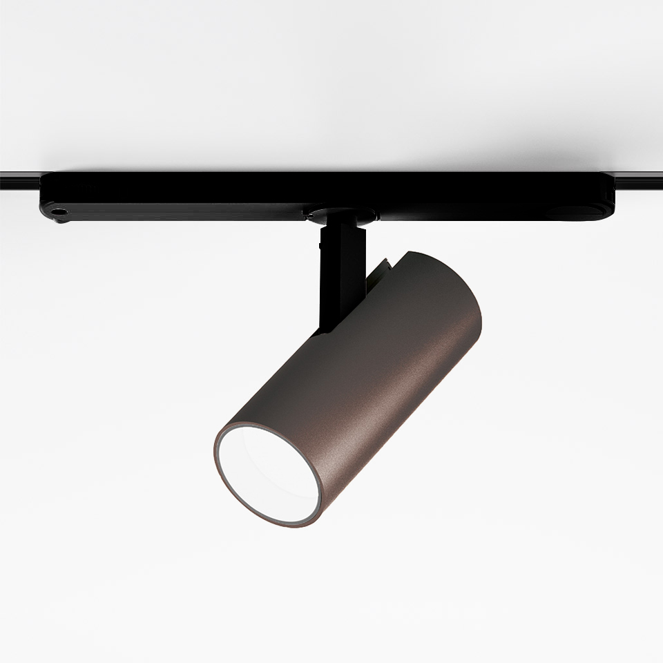 Faretto Artemide Vector Track 230V: testa cilindrica LED color bronzo su supporto a binario nero, inclinata verso il basso per illuminazione direzionale