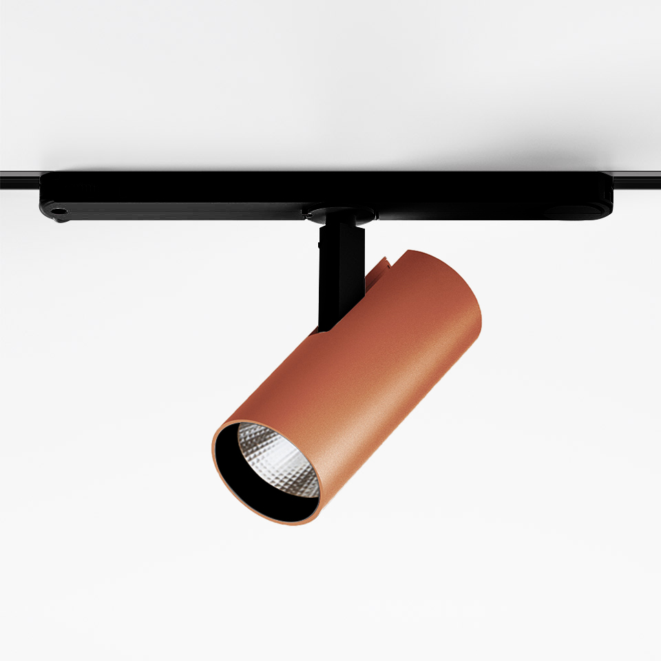 Artemide Vector Track 230V: faretto LED cilindrico color terracotta montato su binario nero, testa orientabile con lente sfaccettata