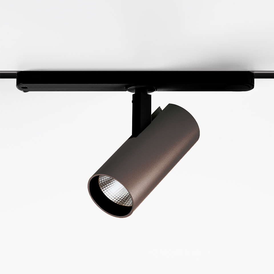 Artemide Vector Track 230V: faretto LED cilindrico bronzo montato su binario nero, testa orientabile con lente sfaccettata