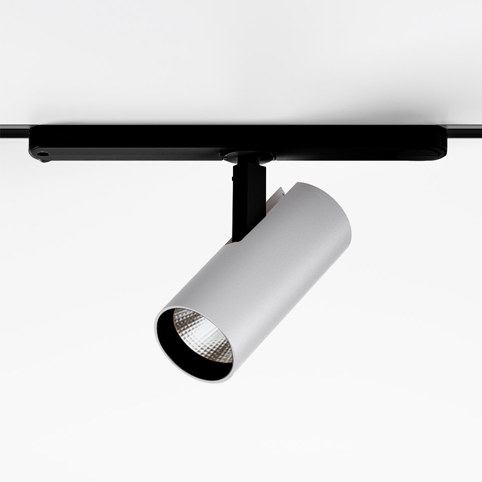 Artemide Vector Track 230V: faretto LED cilindrico bianco montato su binario nero, inclinato verso il basso per illuminazione direzionale