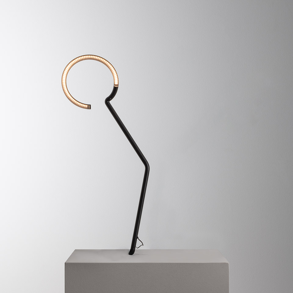 Artemide Vine Light table lamp: black angular stem supporting a warm LED circular ring, sculptural minimalist design on concrete base