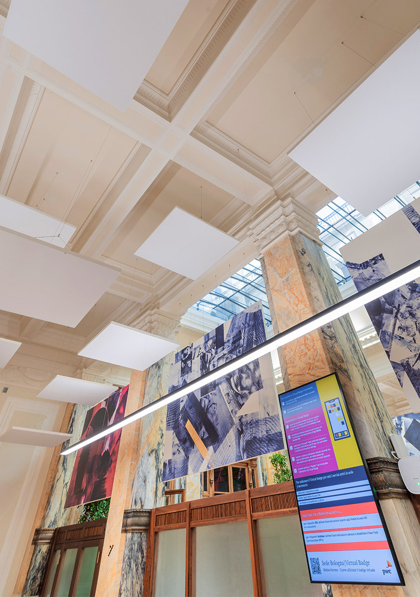 Grand interior hall with coffered ceiling, linear LED lighting strip, marble columns, digital displays, and large photographic wall panels.