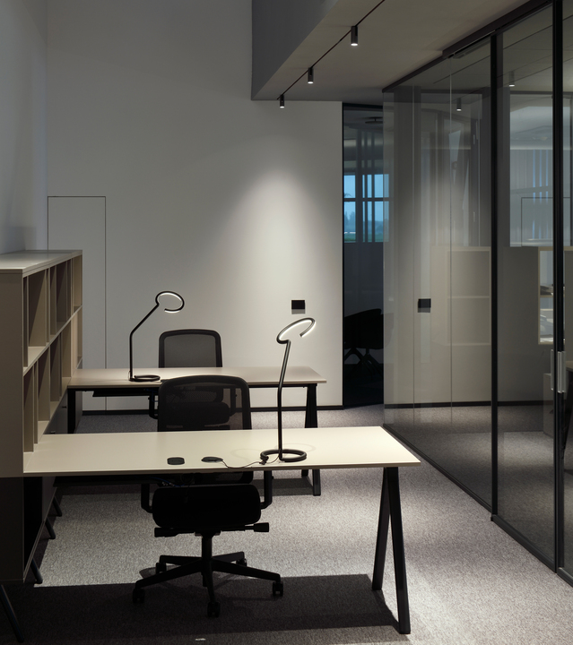 Immagine di postazioni di lavoro illuminate da Turn Around + Vector e da delle Vine Light da tavol.