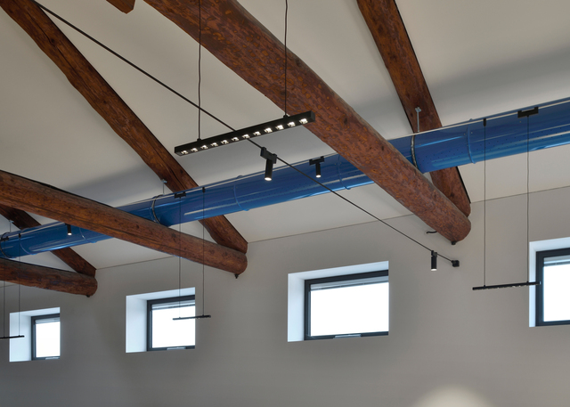 Immagine dell'ufficio con le capriate in legno illuminato con il sistema di Funivia.