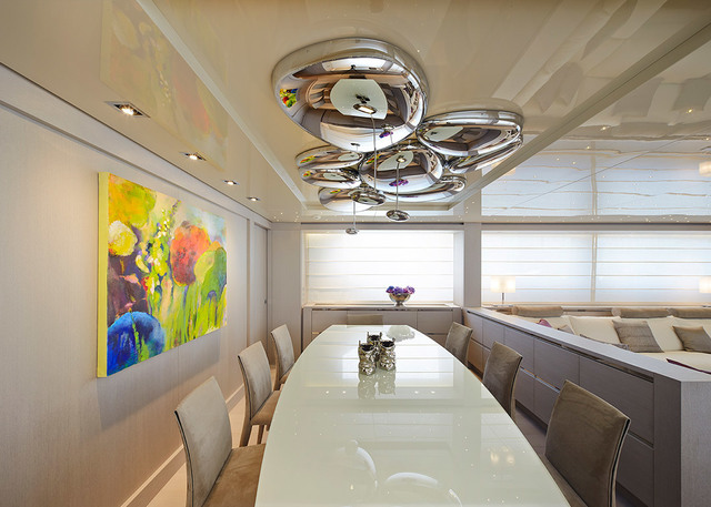 Sala da pranzo di uno yacht con lampadario Artemide Mercury in cromo lucido sospeso su un tavolo ovale bianco circondato da sedie beige.