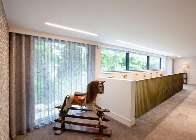 Modern living space with Artemide recessed linear ceiling lights, large windows with sheer curtains, and a vintage rocking horse.