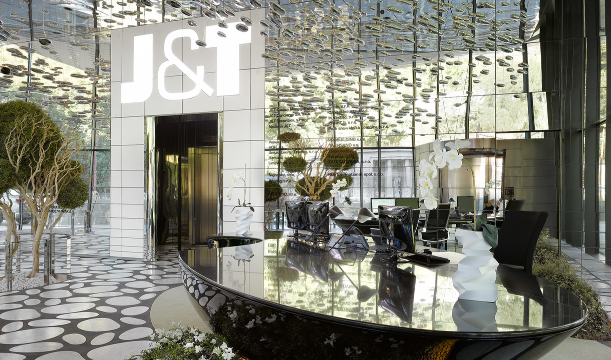 Lobby dell'edificio J&T con soffitto riflettente, elegante bancone reception nero, lampade scultoree bianche e pannelli decorativi a specchio