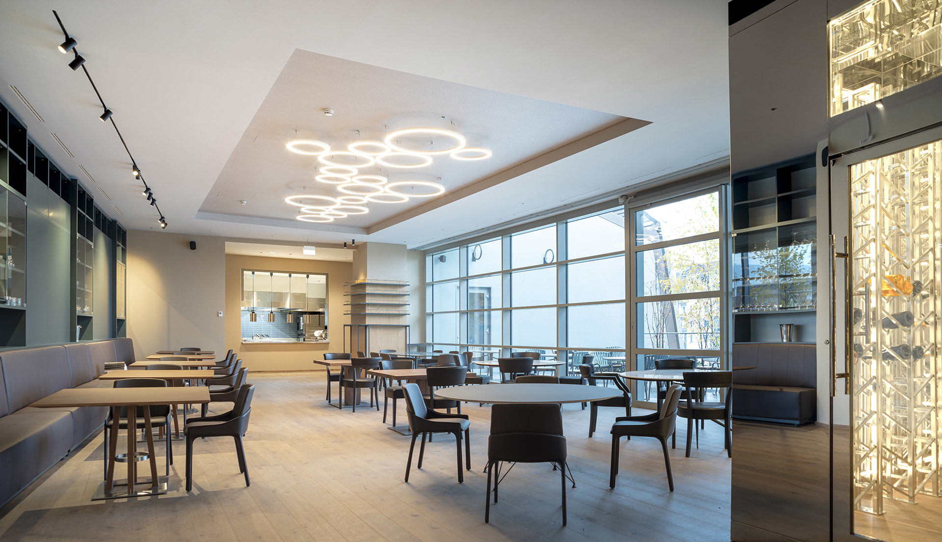 Modern restaurant interior with Artemide circular LED pendant lights arranged in a cluster on the ceiling, track lighting, and large windows.
