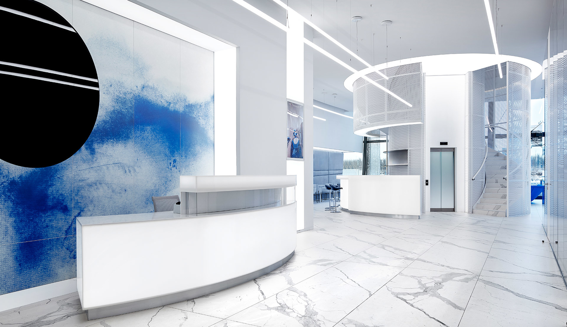 Reception moderna bianca con pavimento in marmo, arte murale blu e luci Artemide circolari a sospensione e lineari a incasso nel soffitto