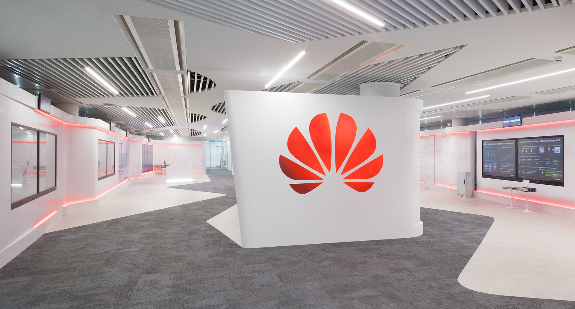 Showroom ufficio Huawei con lampade lineari a soffitto Artemide e illuminazione LED rossa lungo pareti bianche curve