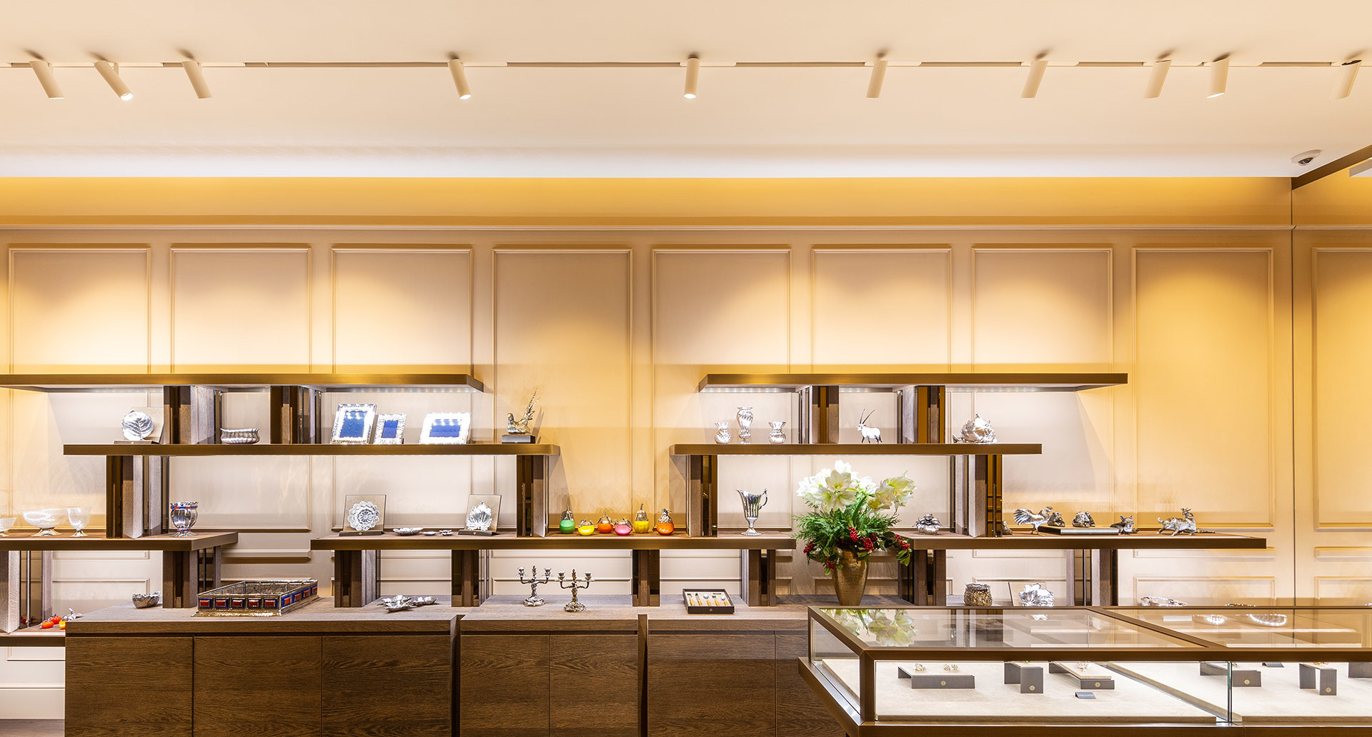 Elegant retail interior with Artemide track spotlights illuminating display shelves and glass counters showcasing luxury goods.