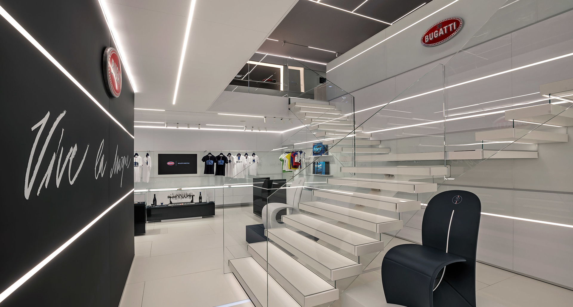 Showroom Bugatti con scala bianca, illuminato da lampade lineari LED Artemide a soffitto che creano pattern geometrici in un interno bianco e nero
