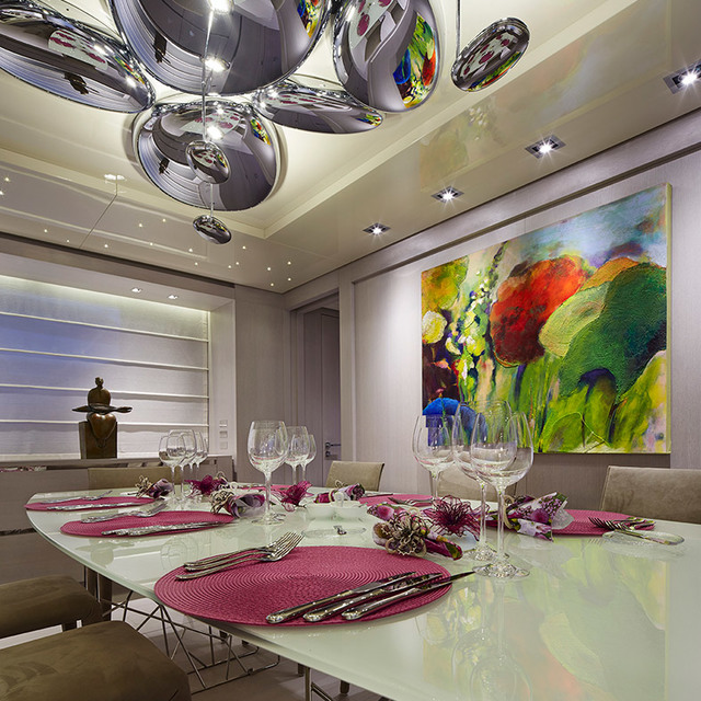 Sala da pranzo elegante con lampadario a grappolo cromato specchiato sopra una tavola apparecchiata con tovagliette magenta e calici di cristallo