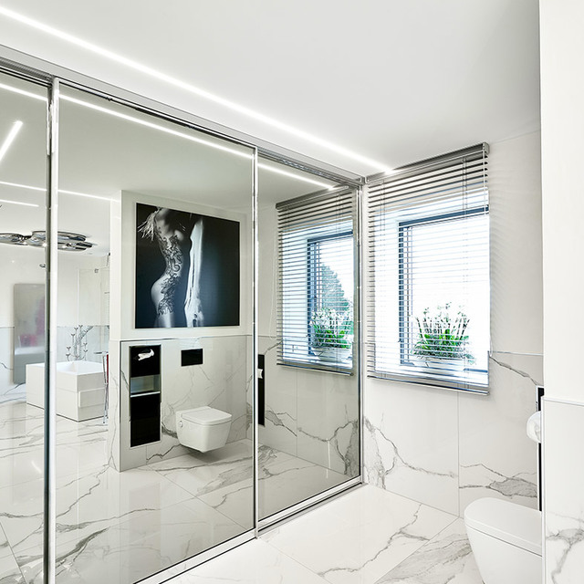 Bagno moderno in marmo bianco con parete in vetro, luce LED lineare a soffitto, veneziane e WC sospeso