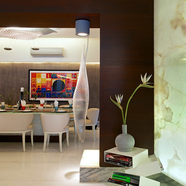 Sala da pranzo con lampada a sospensione Artemide a rete appesa a un portalampada blu a soffitto, che illumina un tavolo elegantemente apparecchiato.