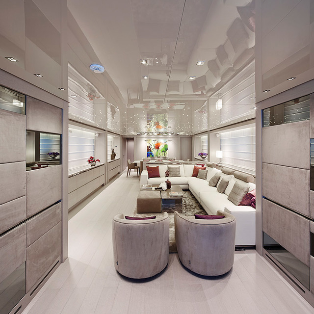 Interno di yacht di lusso con luci a soffitto incassate, grande divano bianco ad angolo, due poltrone rotonde e lampade a sospensione colorate