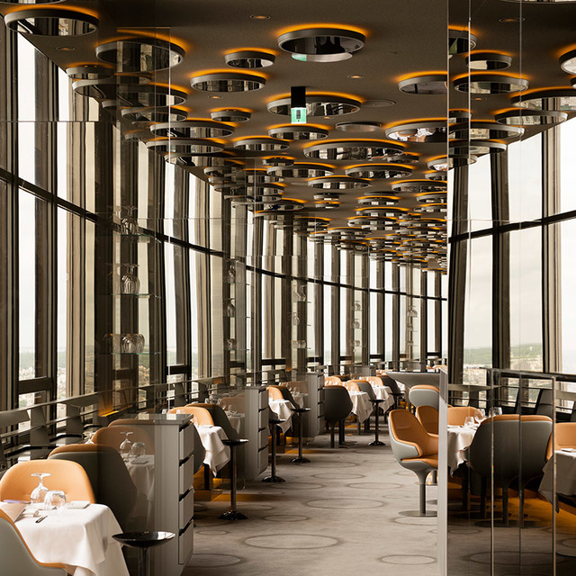 Soffitto di ristorante elegante con file di lampade a sospensione circolari con dettagli dorati, riflesse su colonne a specchio sopra i tavoli.