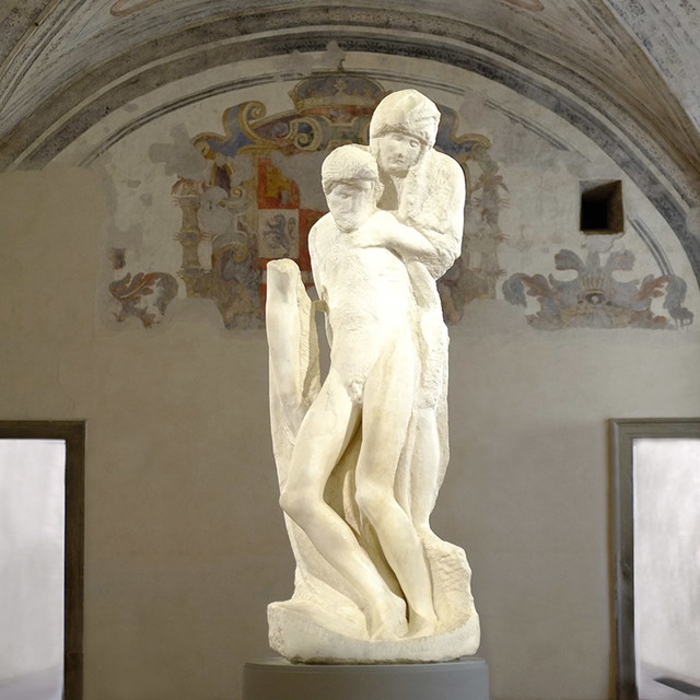 Michelangelo's Rondanini Pietà, an unfinished marble sculpture of two intertwined figures, displayed in a vaulted room with frescoes.
