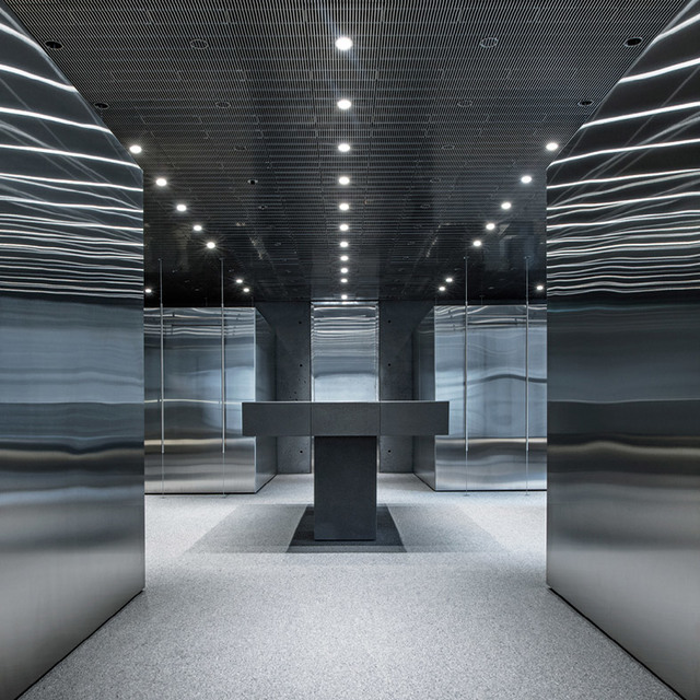 Futuristic interior with mirrored walls reflecting white linear light strips, recessed ceiling spotlights, and a central dark pedestal