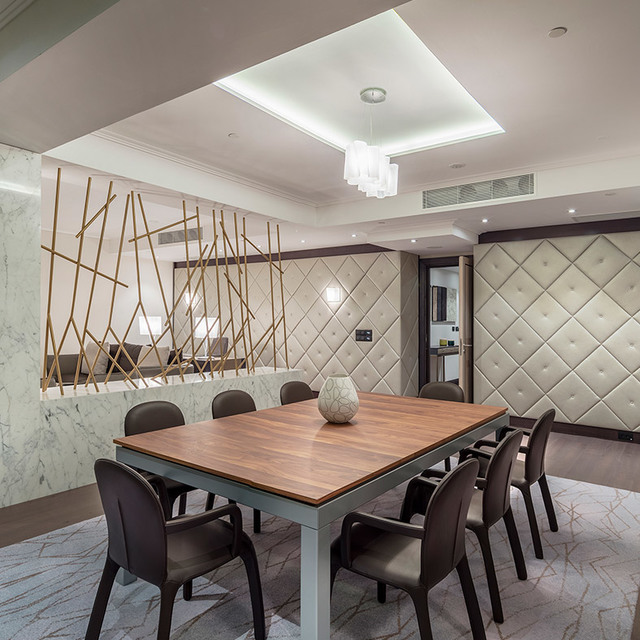 Sala da pranzo elegante con tavolo in noce, sedie scure e lampada a sospensione in vetro a cascata su soffitto a cassettoni.