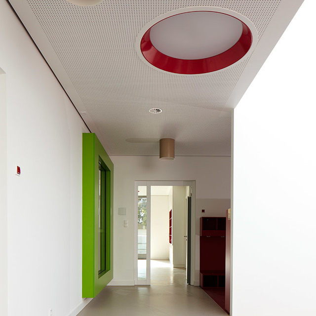 Corridor with Artemide ceiling lamp featuring bold red circular rim and white diffuser, complemented by a small cylindrical pendant light
