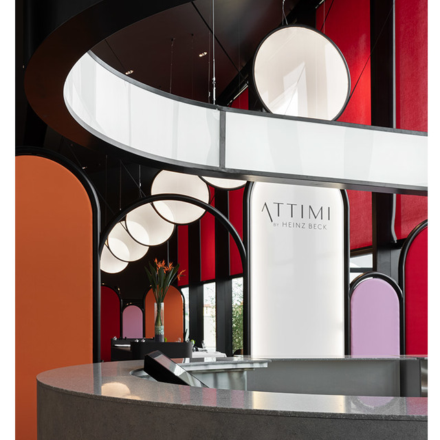 Interno del ristorante Attimi by Heinz Beck con lampade a sospensione circolari con dischi opalini bianchi su strutture ad arco nere, vivace arredo rosso e arancione.