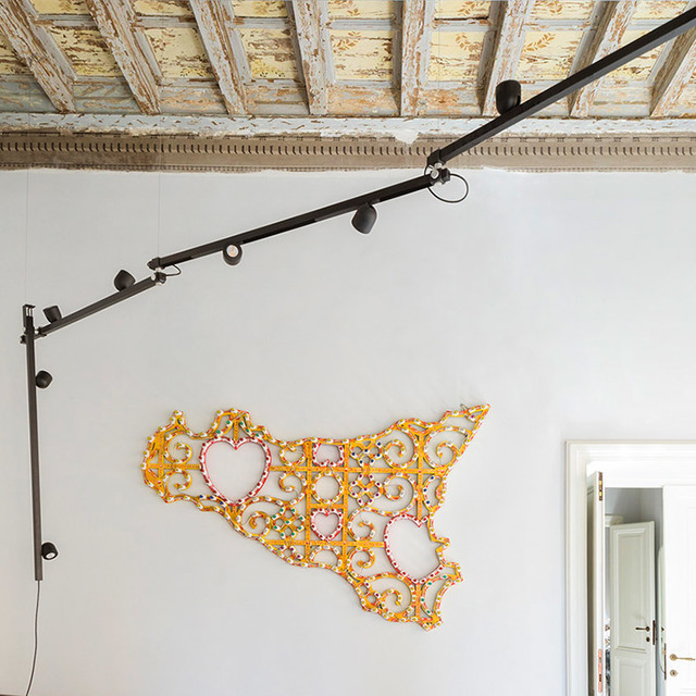 Binario da parete Artemide nero con più faretti orientabili, installato in una stanza con soffitto decorato e opera d'arte murale.