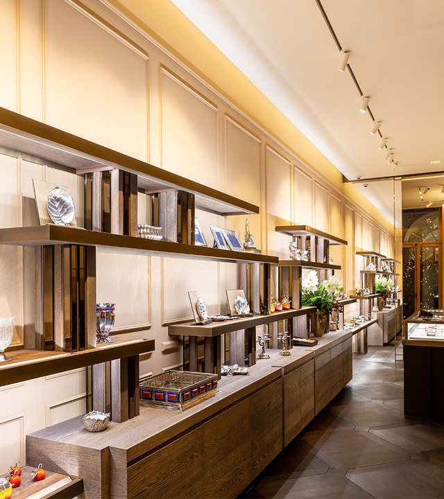 Elegant retail interior with warm-lit display shelves showcasing luxury items, illuminated by Artemide track spotlights and cove lighting.