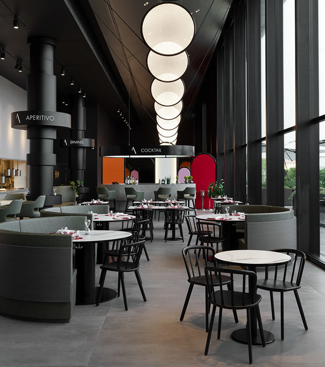 Interno di ristorante moderno con lampade a sospensione sferiche bianche a cascata appese a soffitto alto sopra mobili scuri e tavoli rotondi.