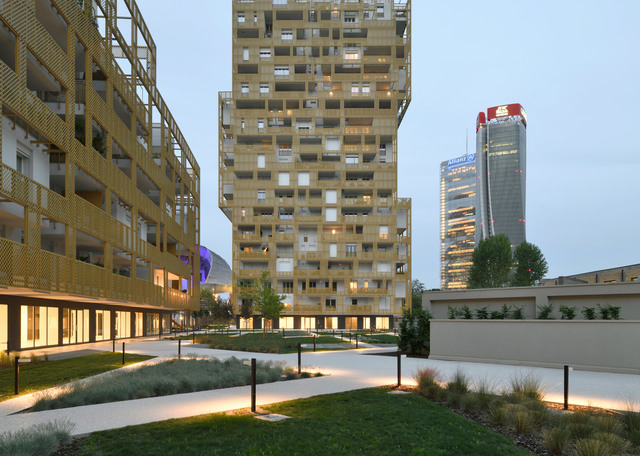 Artemide bollard lights illuminate a modern residential complex courtyard at dusk, with landscaped paths and tall buildings in background