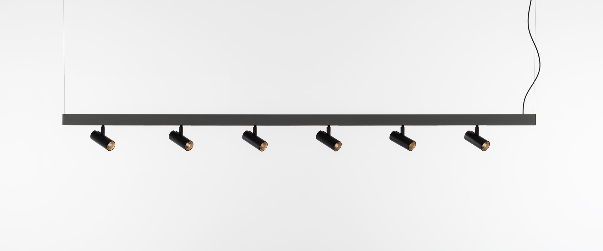 Camera da letto e area lavoro moderna con sistema di binario magnetico Artemide A.24 a soffitto, veneziane grigie e mobili bianchi minimalisti
