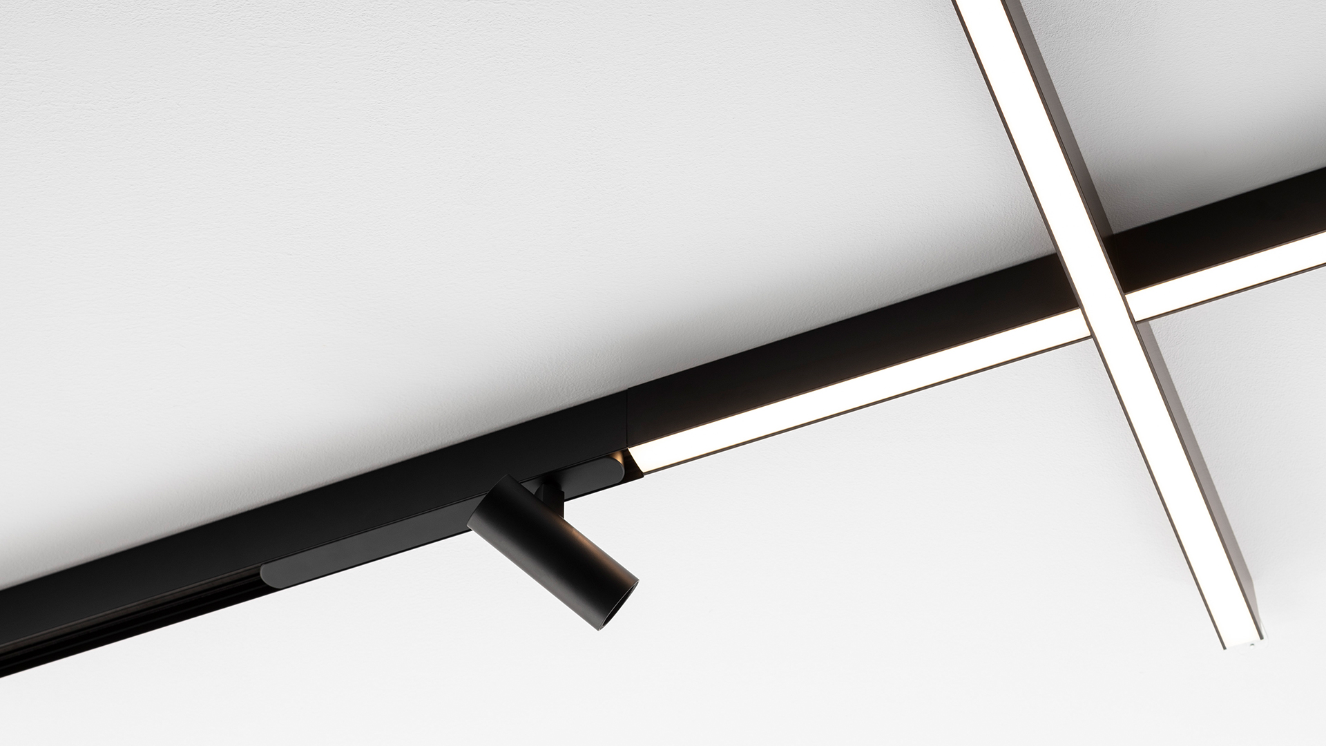 Luci lineari LED Artemide A.24 illuminano un elegante showroom automotive con motore Bugatti, modellini e auto da corsa dietro vetro