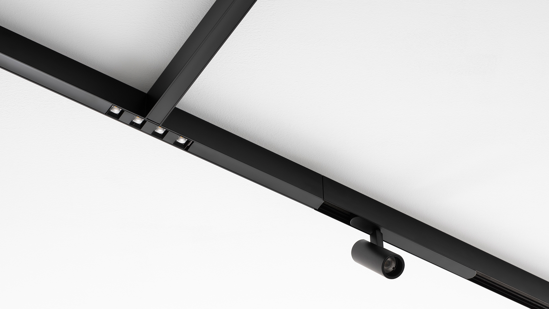 Artemide A.24 lighting system: ceiling-mounted rounded rectangular frame and circular wall fixture emitting white light in a dark concrete room