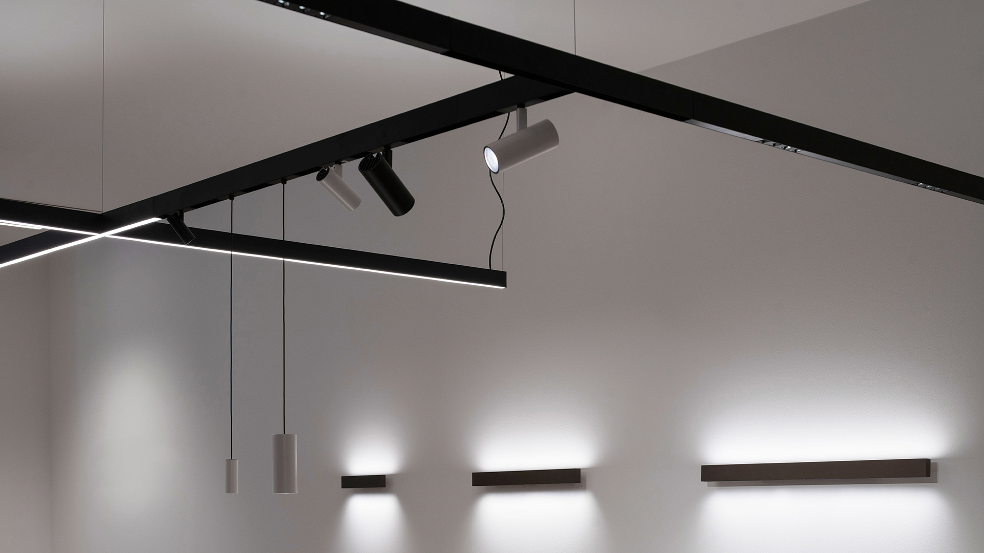Artemide A.24 Emissione Diffusa: nastri LED sinuosi sospesi da soffitto scuro in interno a tema industriale con accenti gialli
