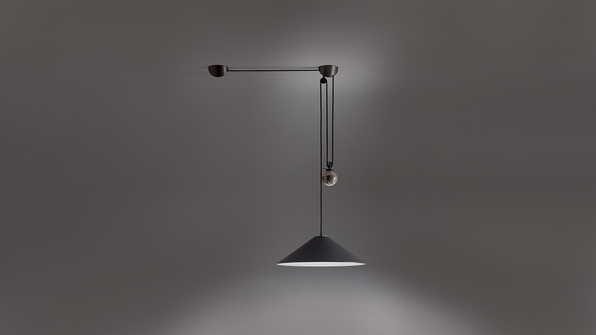 Aggregato pendant lamp by Artemide: dark conical shade suspended by pulley counterweight system on a wall-mounted black metal arm